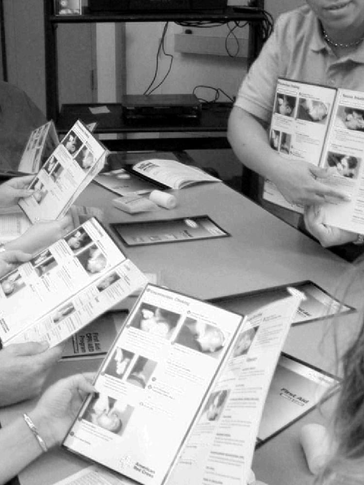 American Red Cross first aid class reviewing course booklets with an instructor