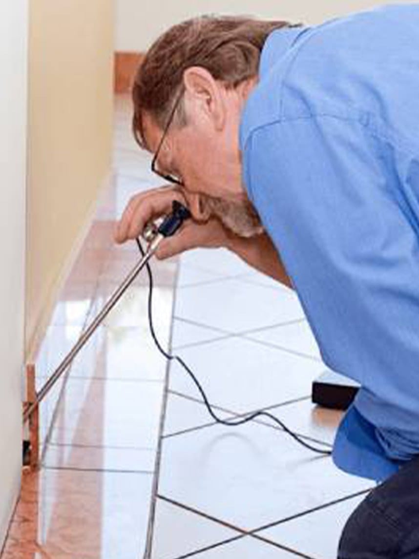 Tyrrells building consultant testing a tiled floor with a moisture meter