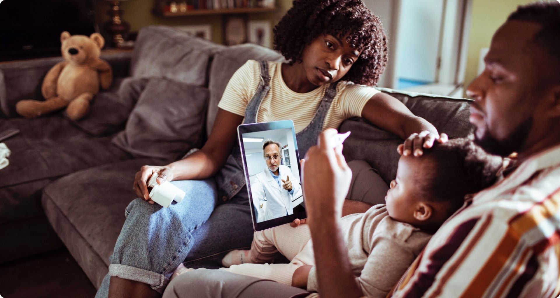 Family on a sofa on a video call with a doctor