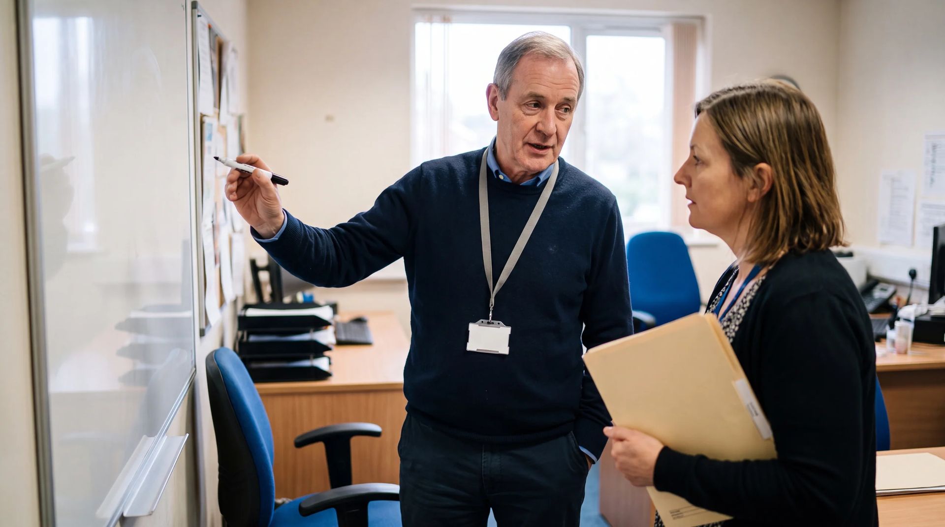 Team leader reviewing a plan with a colleague at a whiteboard