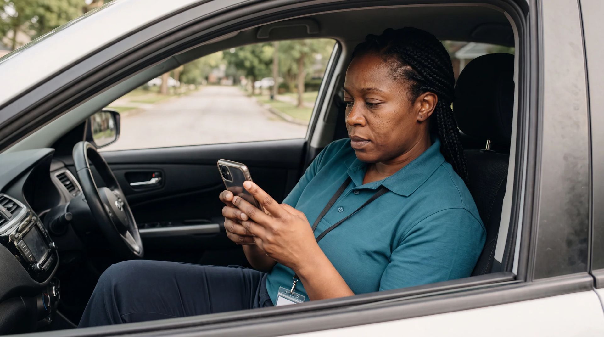 Home care worker logging visit notes on smartphone in parked car