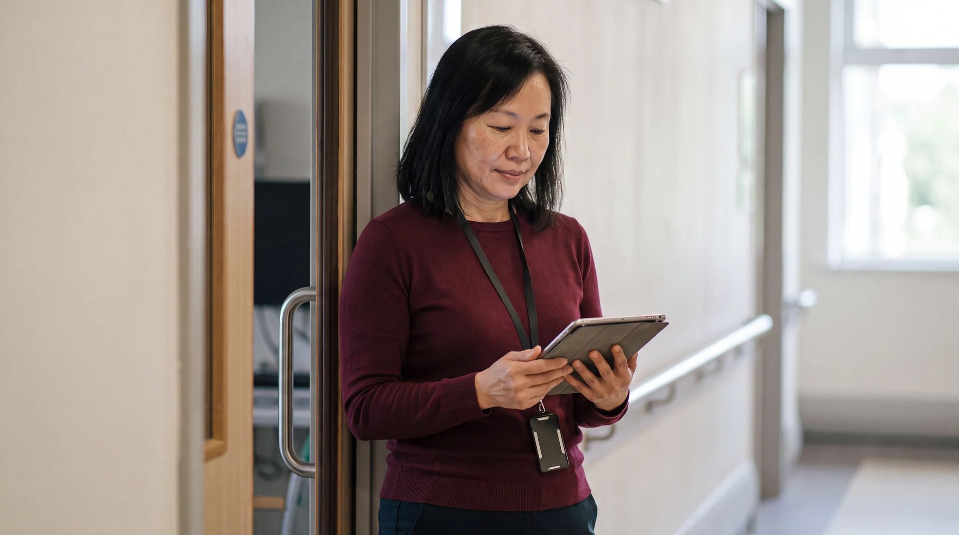 Staff member using a tablet in a doorway off a corridor