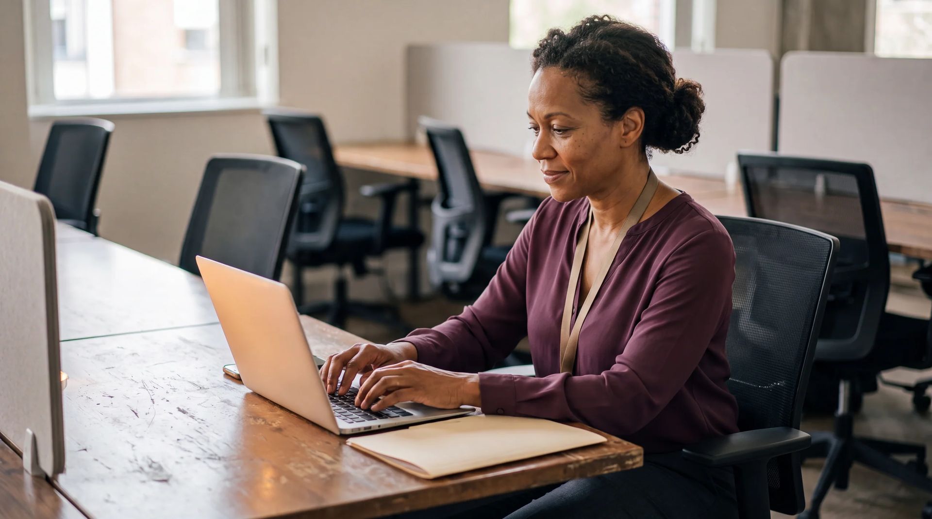 Staff member typing on a laptop in a shared office