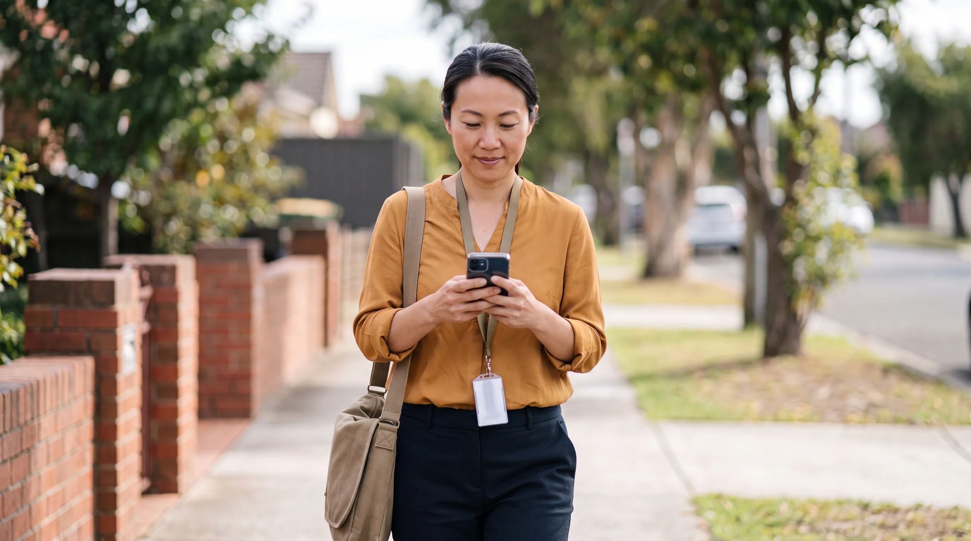 Staff member checking a smartphone while walking along a street