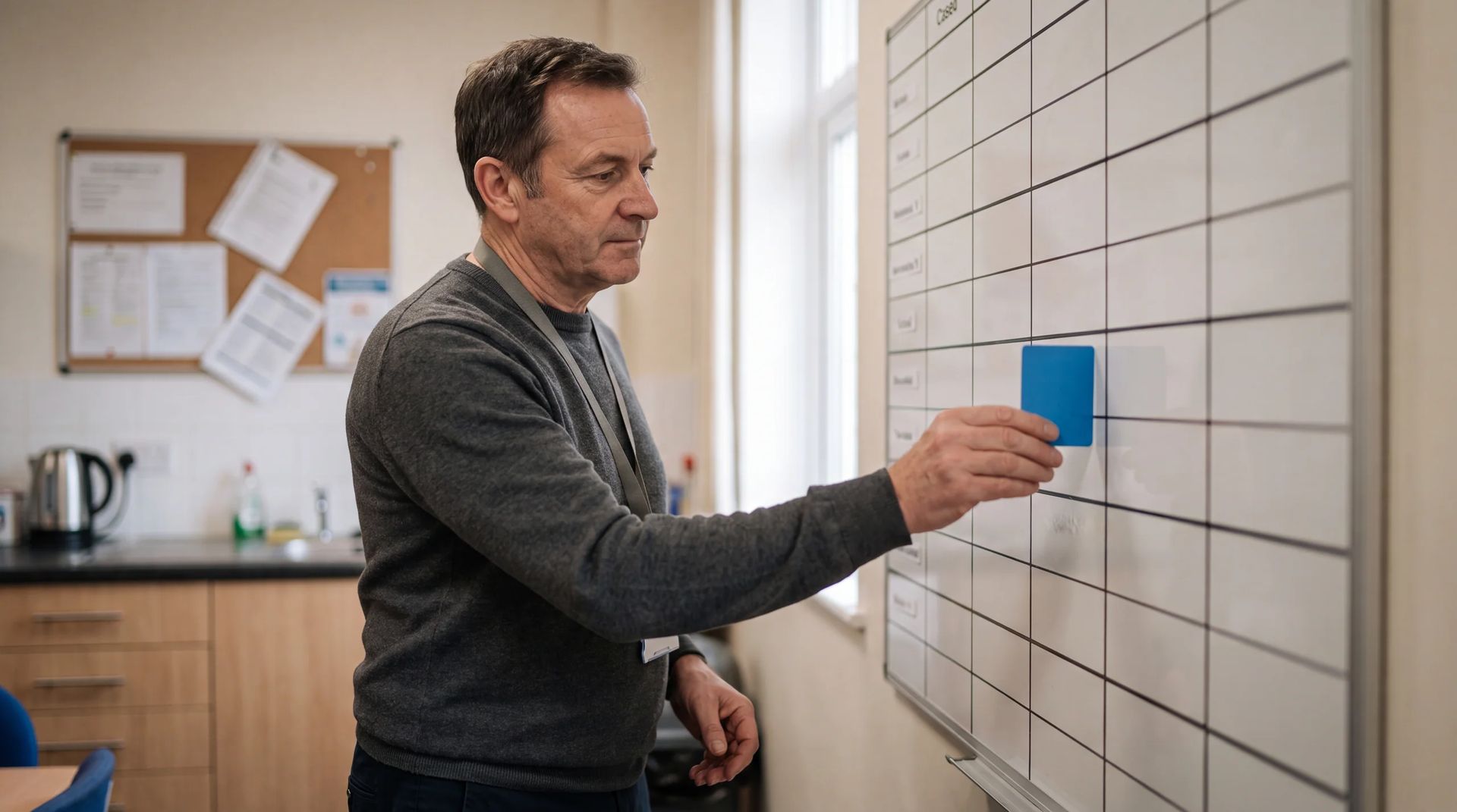 Staff member placing a blank card on a wall planning board