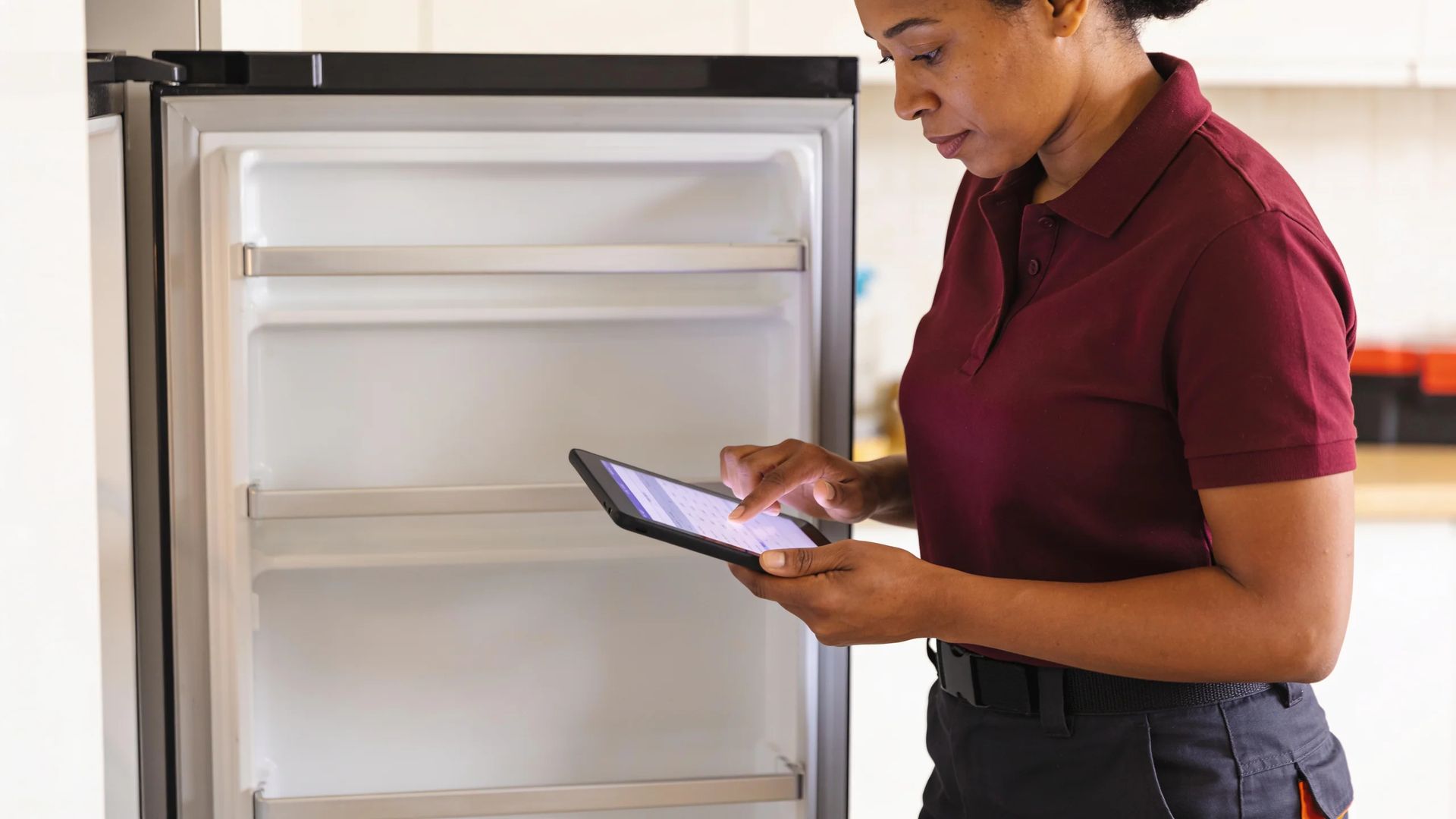 Technician using a tablet beside an open fridge