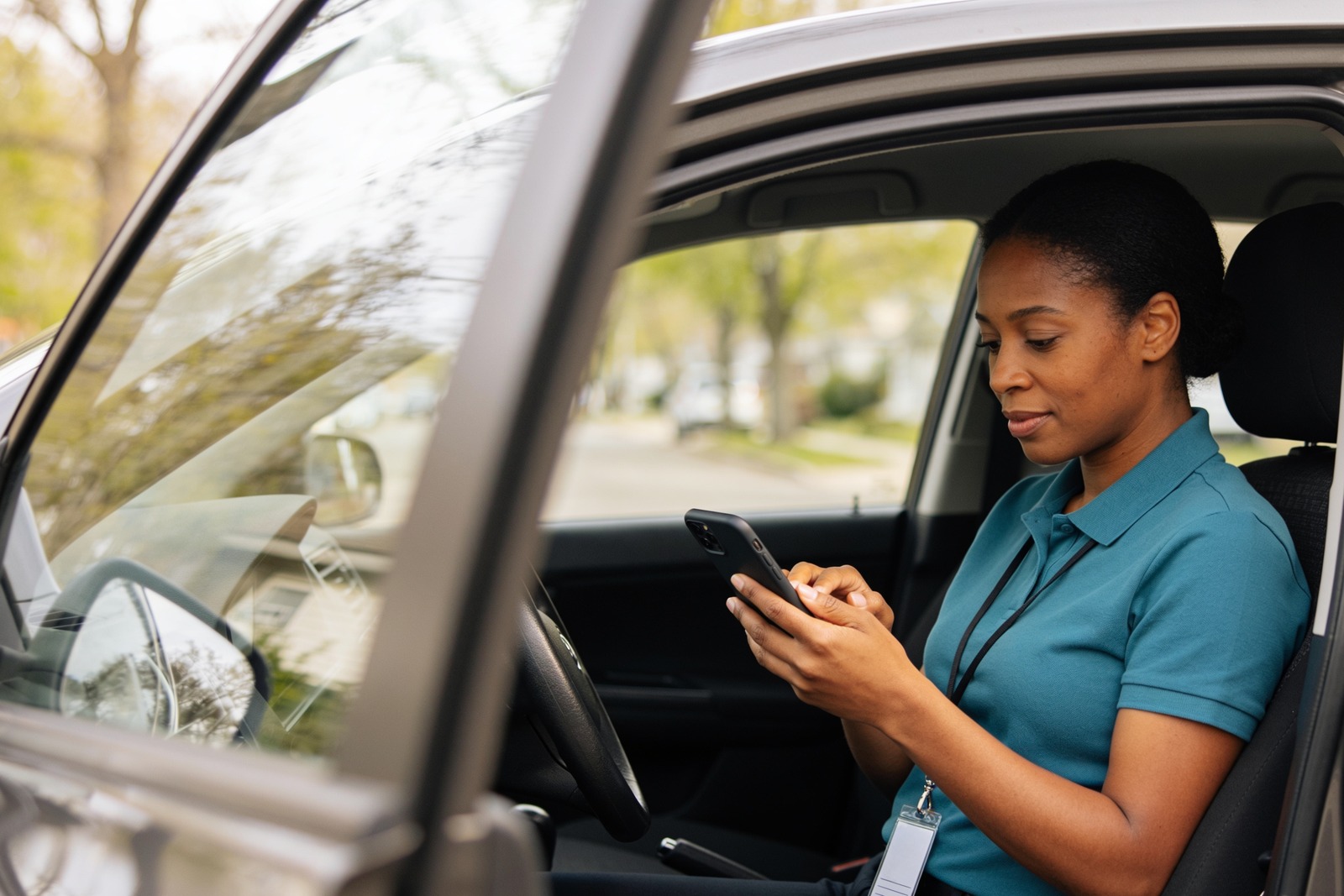 Home care worker messaging on her phone in a parked car